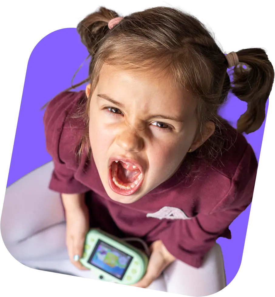 A child in a maroon shirt sits cross-legged, holding a green gaming device.